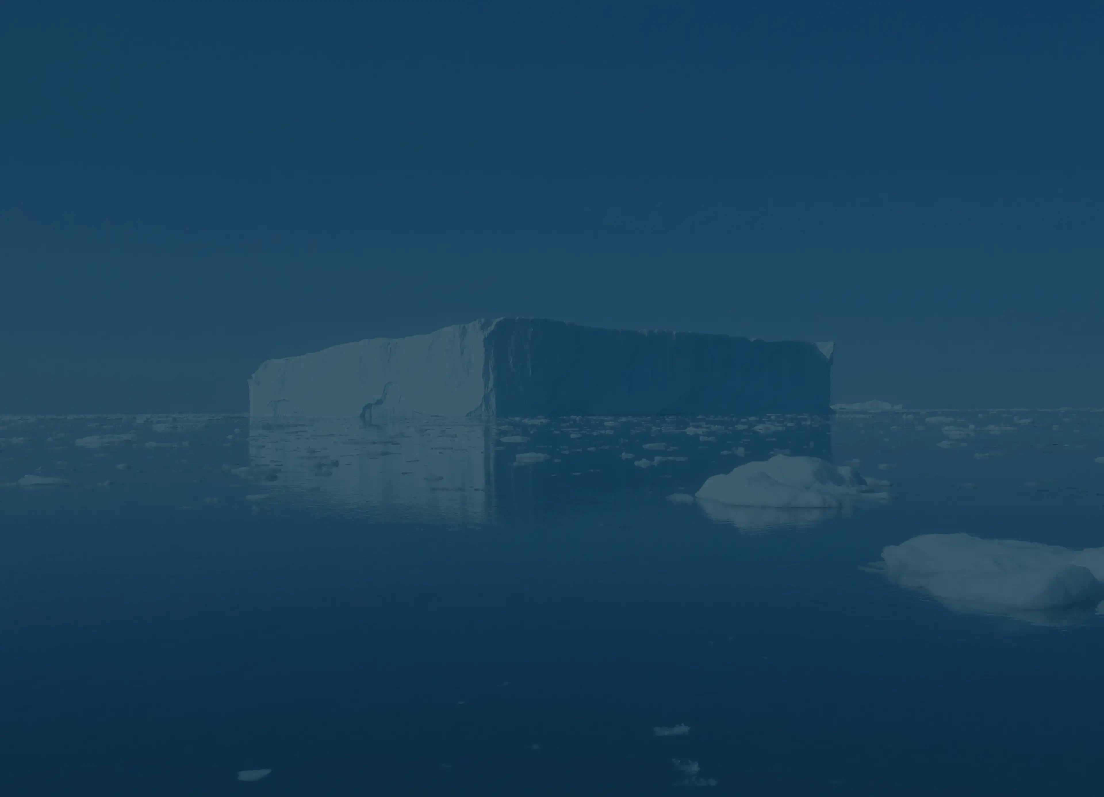 Iceberg floating in the ocean with a dark blue tint