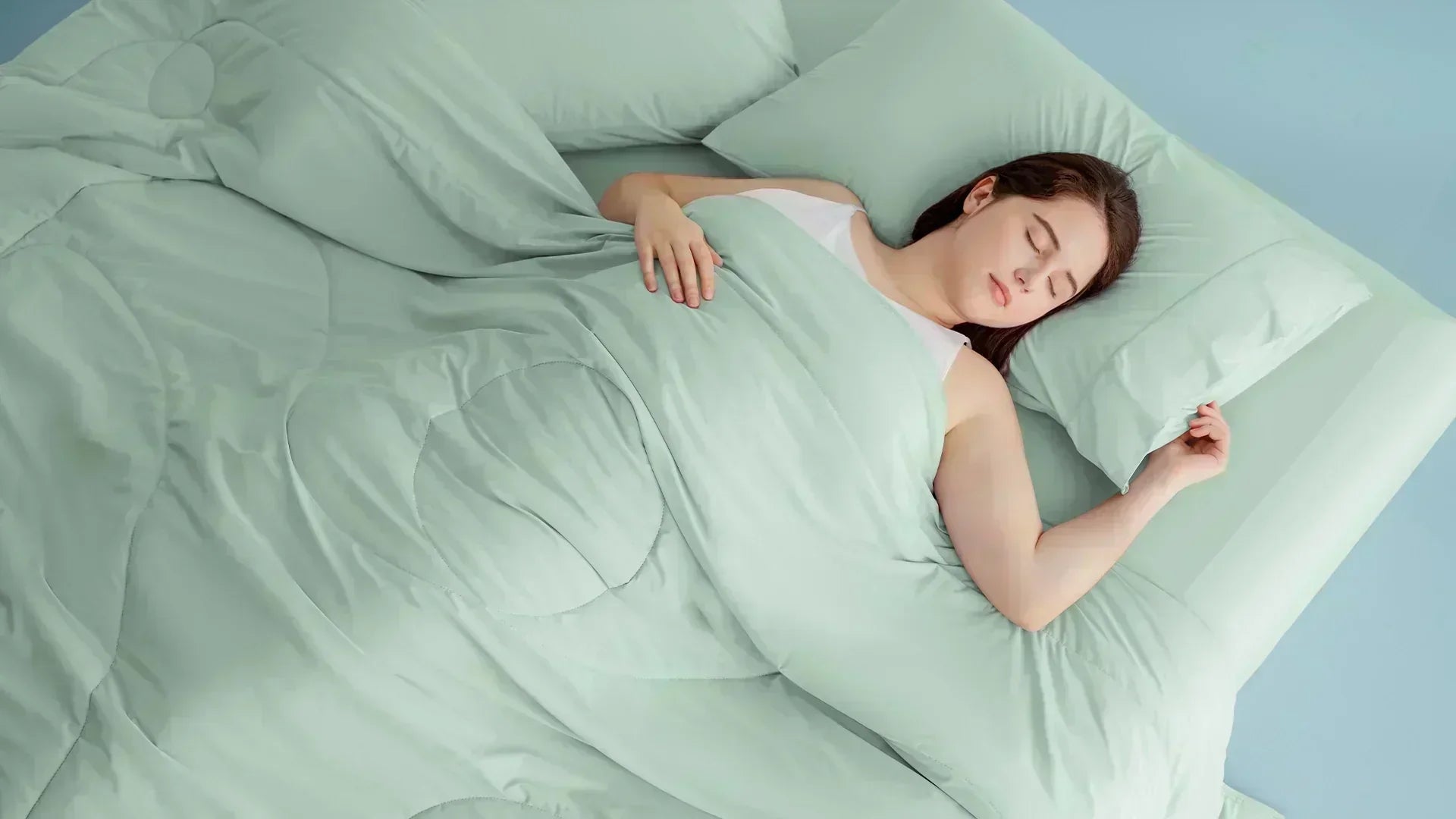 Woman sleeping deeply on a breathable cooling pillow and matching mint green bedding set