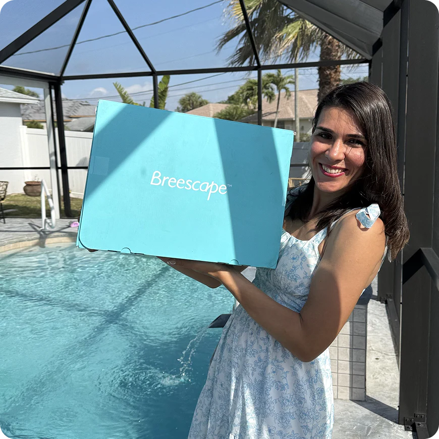 Woman holding a blue box with 'Breescape' branding by a pool.
