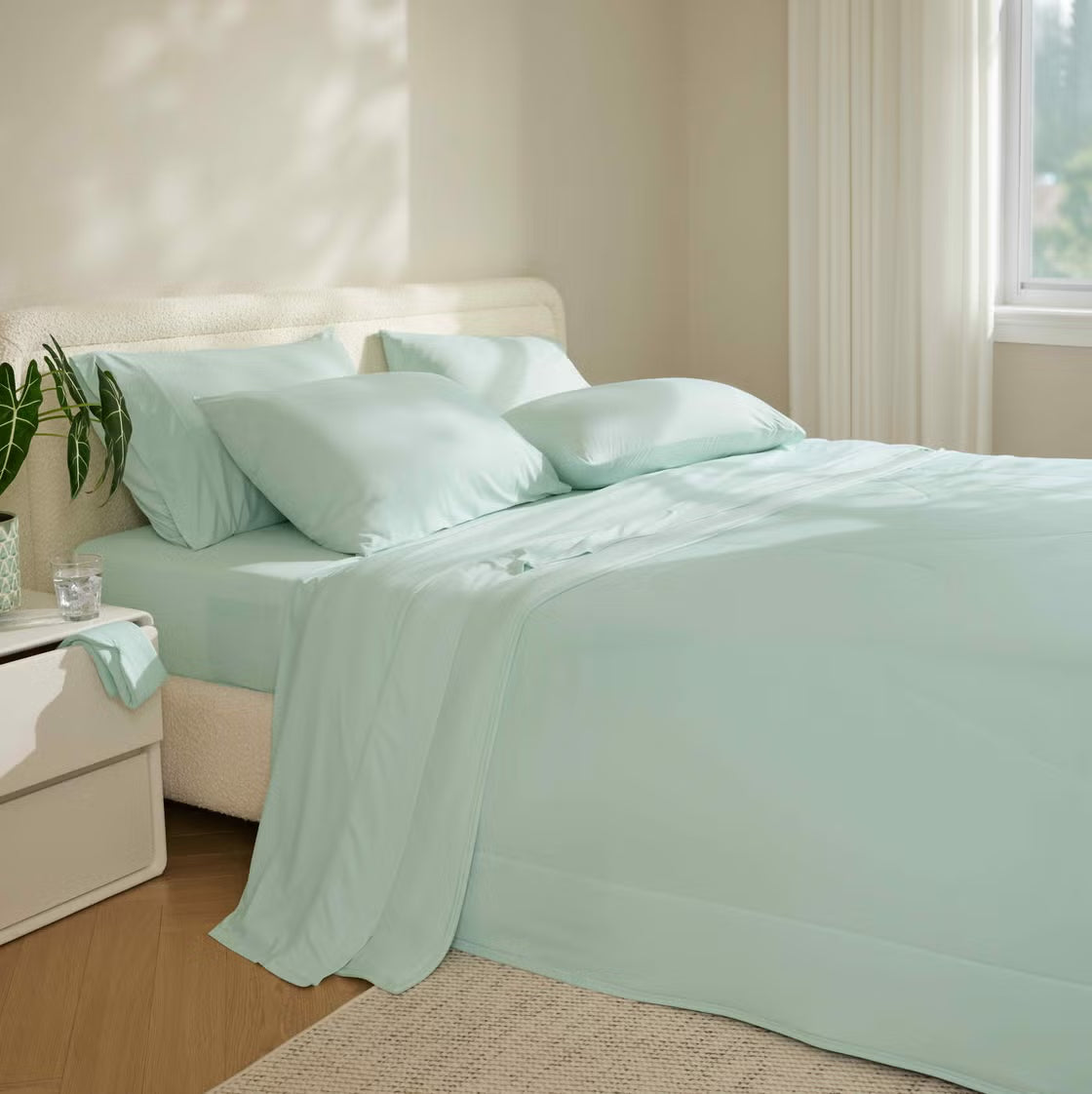 Bed with light green bedding in a well-lit bedroom