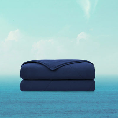 Folded navy blue blanket on a light blue gradient background