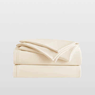Stack of Breescape cooling sheets in ivory. Breathable bedding designed for hot sleepers.