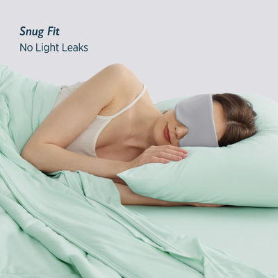 Woman sleeping with Breescape misty grey cooling eye mask and mint green bedding. Snug fit, no light leaks. Ideal for hot sleepers.