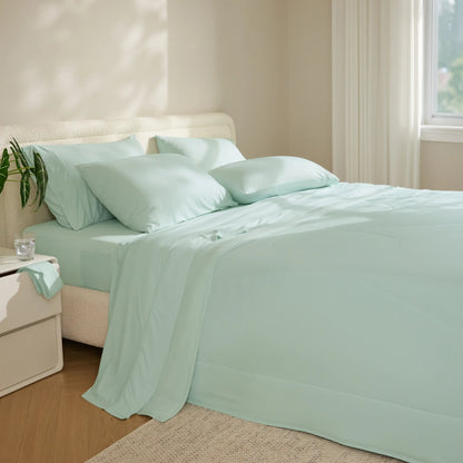 Mint green bedding set on a bed in a bedroom with a nightstand and plant.  #color_mint-green