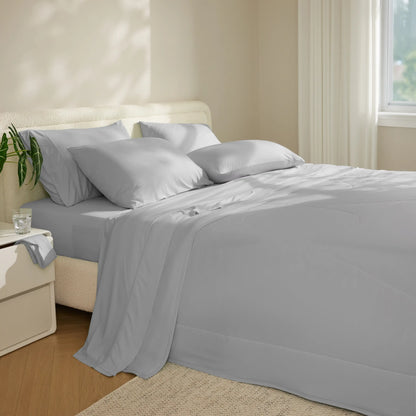 Gray bedding set on a bed in a bedroom with a nightstand and plant. #color_misty-grey